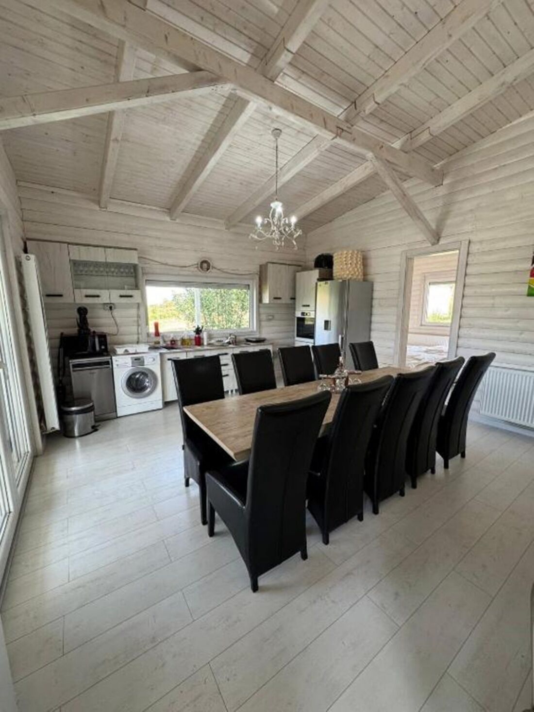 Un'ampia cucina con zona pranzo, travi a vista in legno e un lampadario.