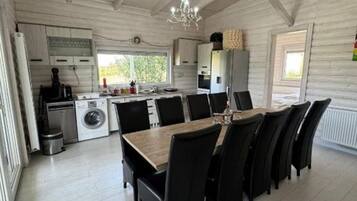 Un'ampia cucina con zona pranzo, travi a vista in legno e un lampadario.