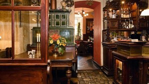 A traditional bar area with wooden furniture, a green cabinet with glass doors, and a floral centerpiece on a table. - Dicker Mann Hotel Zum Blauen Krebs (Regensburg)