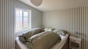 A bedroom with a single bed, a nightstand, a lamp, and a window with a view of trees. - Beach front home in Vikebygd with WiFi (Vikebygd)