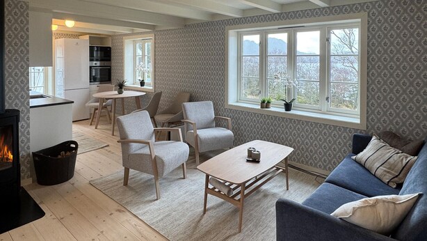 A cozy living room with a fireplace, a sofa, a coffee table, and a dining area with chairs and a table. - Beach front home in Vikebygd with WiFi (Vikebygd)