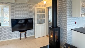 A living room with a TV, a fireplace, and patterned wallpaper. - Beach front home in Vikebygd with WiFi (Vikebygd)