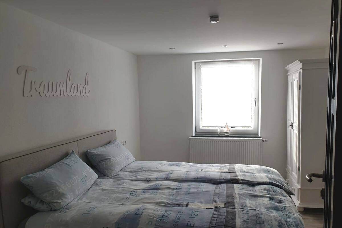 Een slaapkamer met een bed, een raam en een radiator.