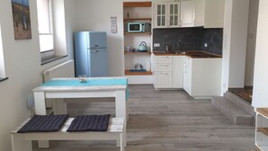 Een kleine keuken met witte kastjes, een blauwe koelkast, een magnetron en een spoelbak.