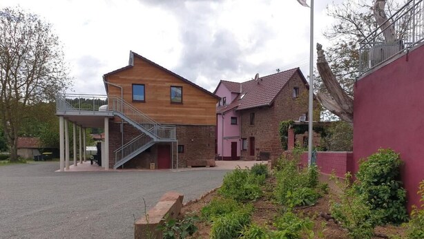 Een woonwijk met een herenhuis met houten gevel en een roze gebouw op de achtergrond.