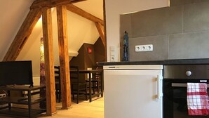Een moderne keuken met een witte koelkast, een inbouwoven en een houten balkenplafond.
