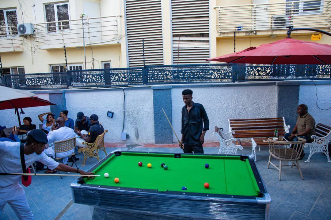 A pool table with balls, surrounded by outdoor seating and a red umbrella.