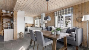 A cozy interior with a wooden ceiling, a dining area with a table and chairs, a sofa, and a kitchen in the background. - Cozy home in Rauland with sauna (Rauland)