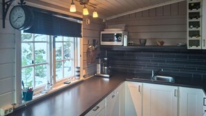 Una cocina con ventana, un reloj, un microondas y una cafetera.