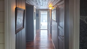 Un pasillo con suelo de madera, un cuadro enmarcado a la izquierda y una puerta a la derecha.