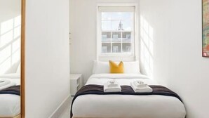 Une chambre d’hôtel avec un lit, une fenêtre et une vue sur les bâtiments environnants.