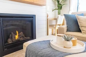 A living room with a fireplace, a sofa, a coffee table, and a plant.
