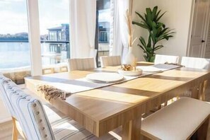 A dining area with a wooden table, white chairs, and a view of the sea.