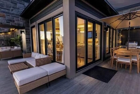 A modern outdoor living area with a sofa, dining table, and chairs.