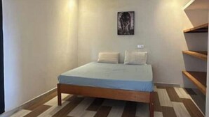 Une chambre à coucher avec un lit, une œuvre d’art accrochée au mur et un plancher en bois.