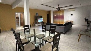 Un salon spacieux avec une table à manger en verre, des sièges confortables, un téléviseur et un canapé.