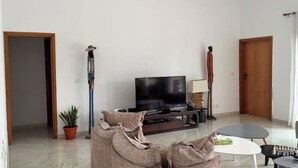 Una sala de estar con un sofá, un televisor, una mesita y una planta en maceta.