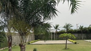 Una cancha de baloncesto rodeada de palmeras y setos.