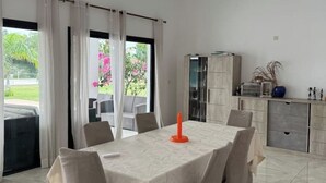 Un comedor con una mesa dispuesta para cuatro personas, un mueble con electrodomésticos de cocina, y vistas al exterior.