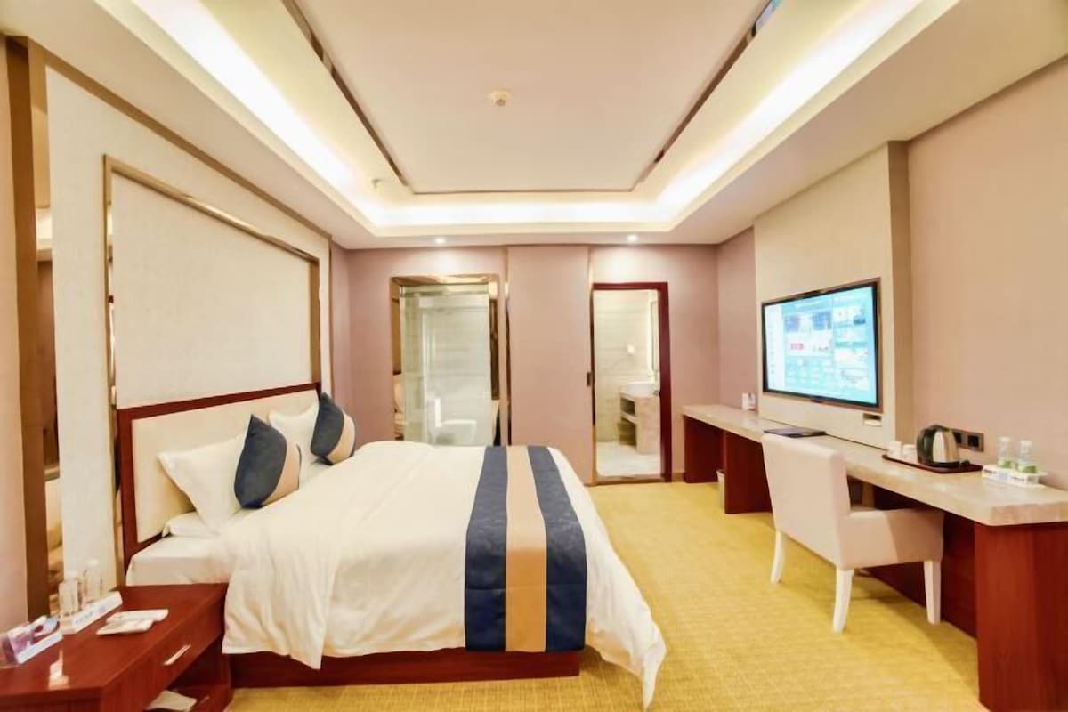 A hotel room with a bed, desk, and television.