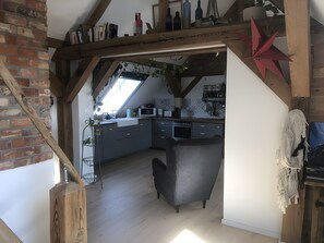 A loft-style kitchen with a high ceiling, exposed wooden beams, and a view to the outside. - Apartment 'Lale' with Lake View, Shared Terrace and Wi-Fi (Wustrow)