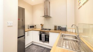 Une cuisine moderne équipée d’appareils électroménagers en acier inoxydable, d’un four à micro-ondes, d’une cuisinière à gaz et d’un évier à deux bacs.