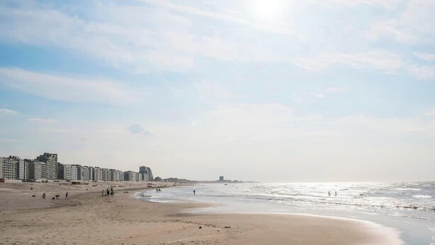 Ein Strand mit einer Reihe hoher Gebäude im Hintergrund.