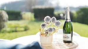 Eine Flasche RENTUS Wein und ein kleiner Vasen mit getrockneten Blumen auf einem Tisch im Freien.