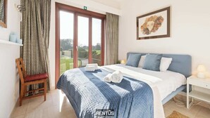 Ein Schlafzimmer mit einem Bett, einem Sessel, einem Fenster und einem Bild an der Wand.