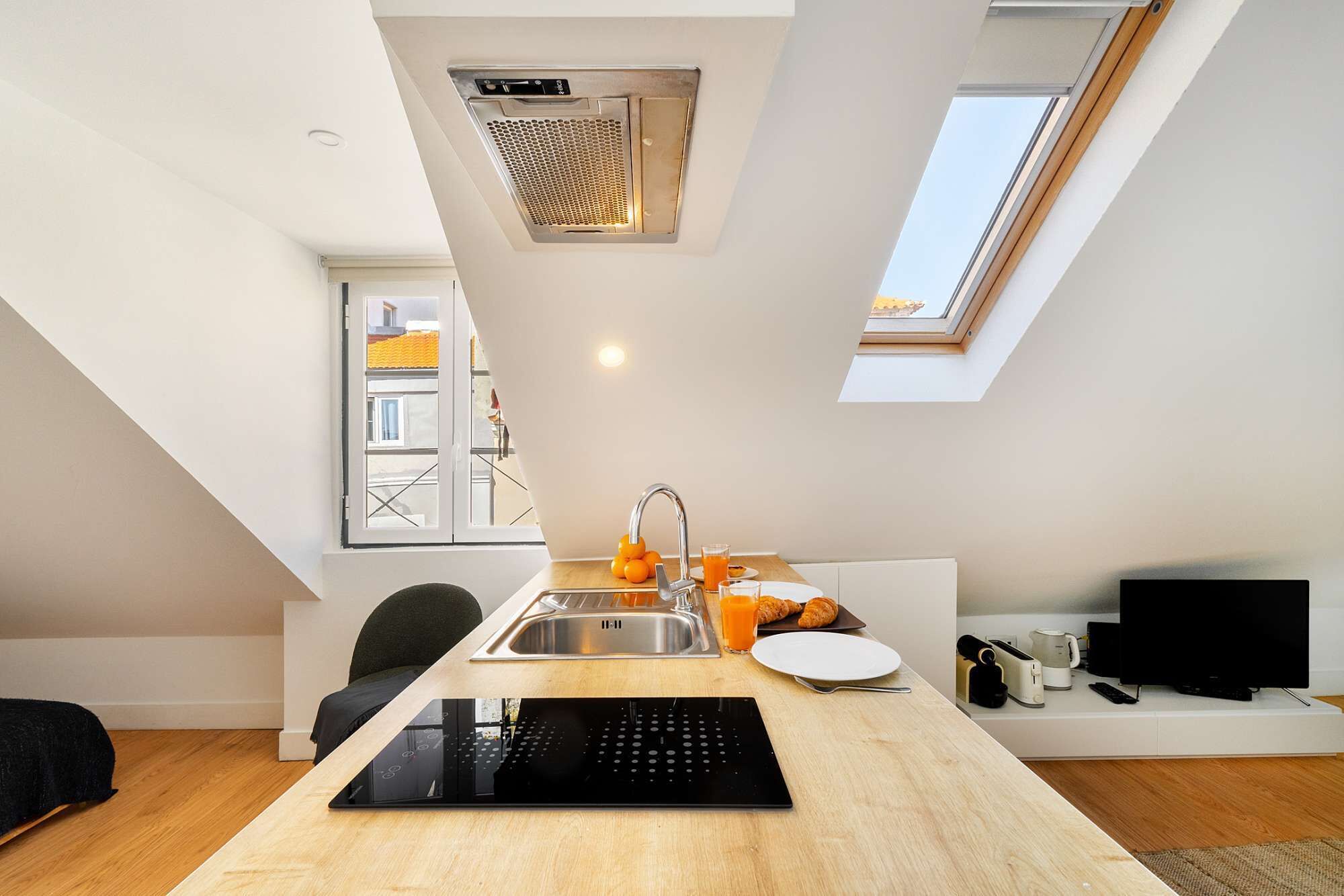 Une cuisine moderne équipée d’une cuisinière intégrée, d’un évier et d’une fenêtre donnant sur un paysage urbain.