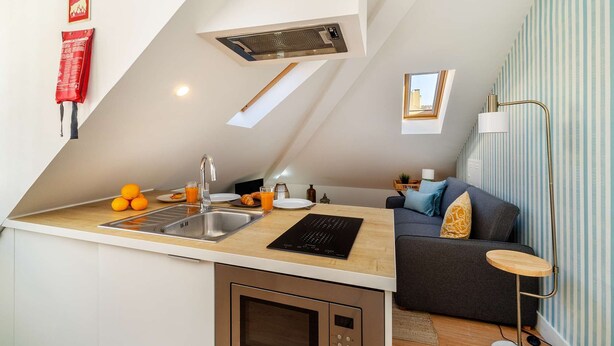 Eine moderne Küche mit Einbauofen, Spüle und Essbereich inklusive Sofa und kleinem Tisch.