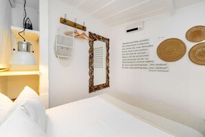 Ein Schlafzimmer mit Bett, einer Pendelleuchte, einem Spiegel und einer Wandklimaanlage.