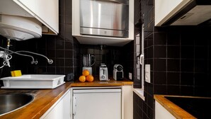 A compact kitchen with a built-in oven, a sink, and a countertop with a blender, toaster, and oranges. - Alfama Retreat Steps from Santa Luzia Viewpoint (Lisbon)