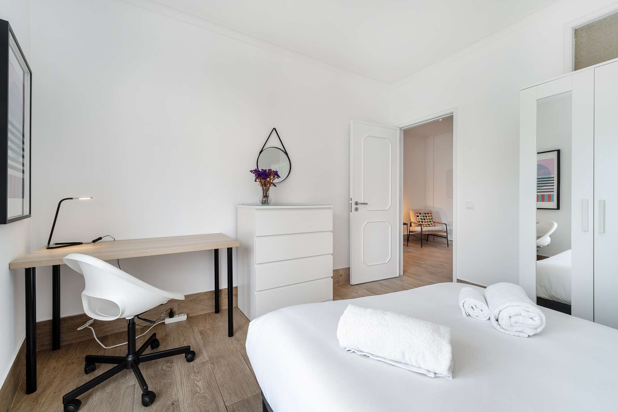 Una camera d'albergo con un letto, una scrivania, una sedia, una cassettiera e uno specchio.