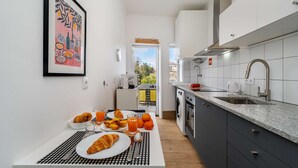 Una cuina moderna amb zona de menjador, una vista per la finestra i una obra d'art emmarcada a la paret.