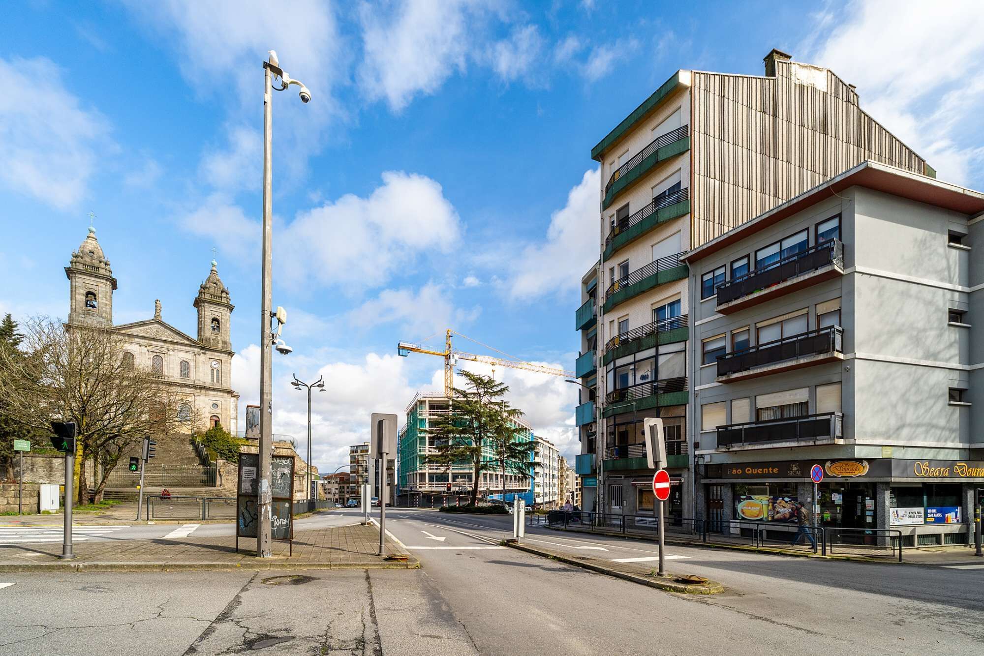 Eine Straße mit einem historischen Kirchengebäude, modernen Gebäuden und einer Baustelle.
