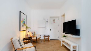 Un saló modern amb un sofà, cadires, un televisor i una taula petita.
