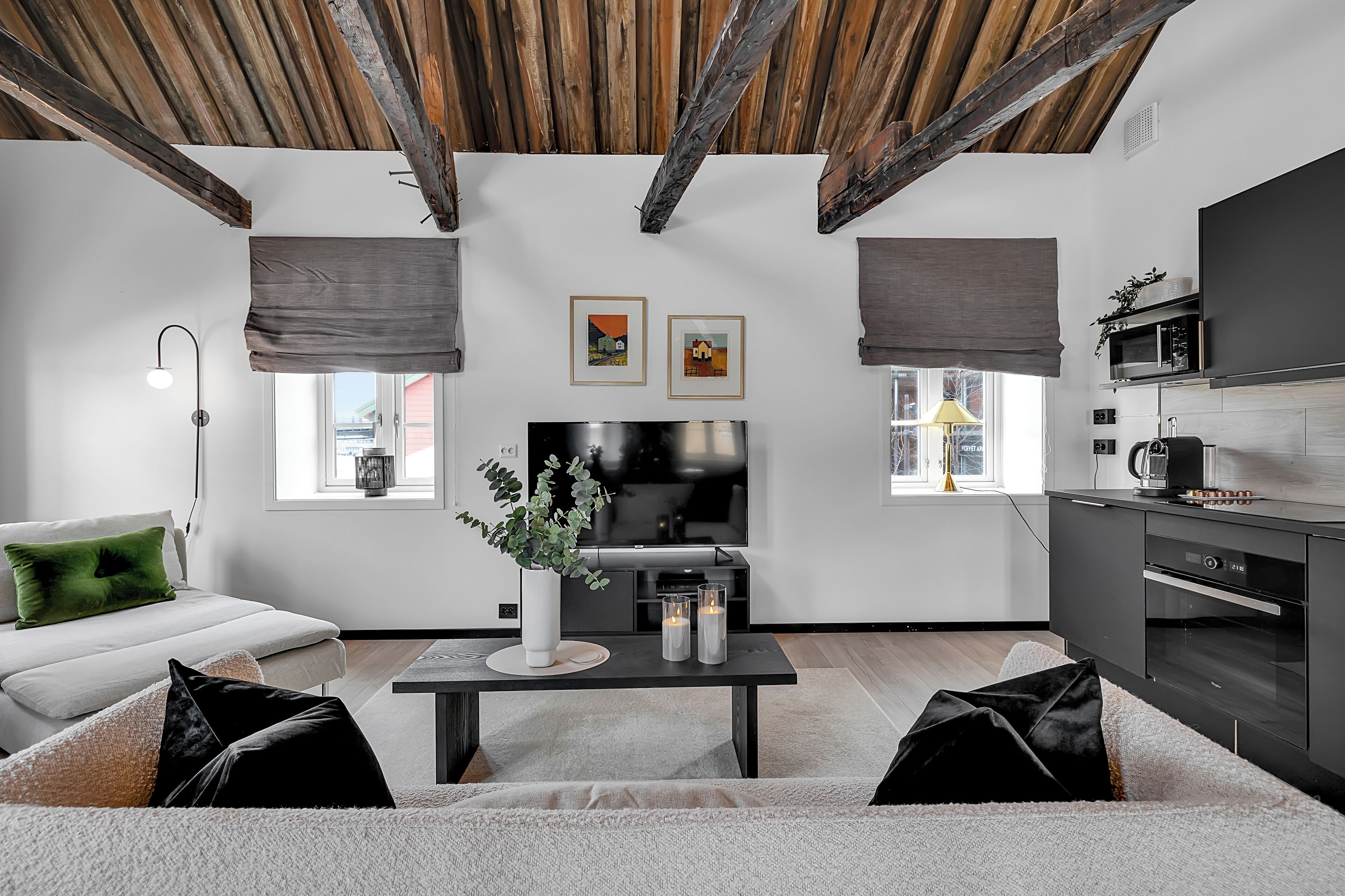 Ein modernes Wohnzimmer mit einer Couch, einem Couchtisch, einem Fernseher und einer Küchenzeile.