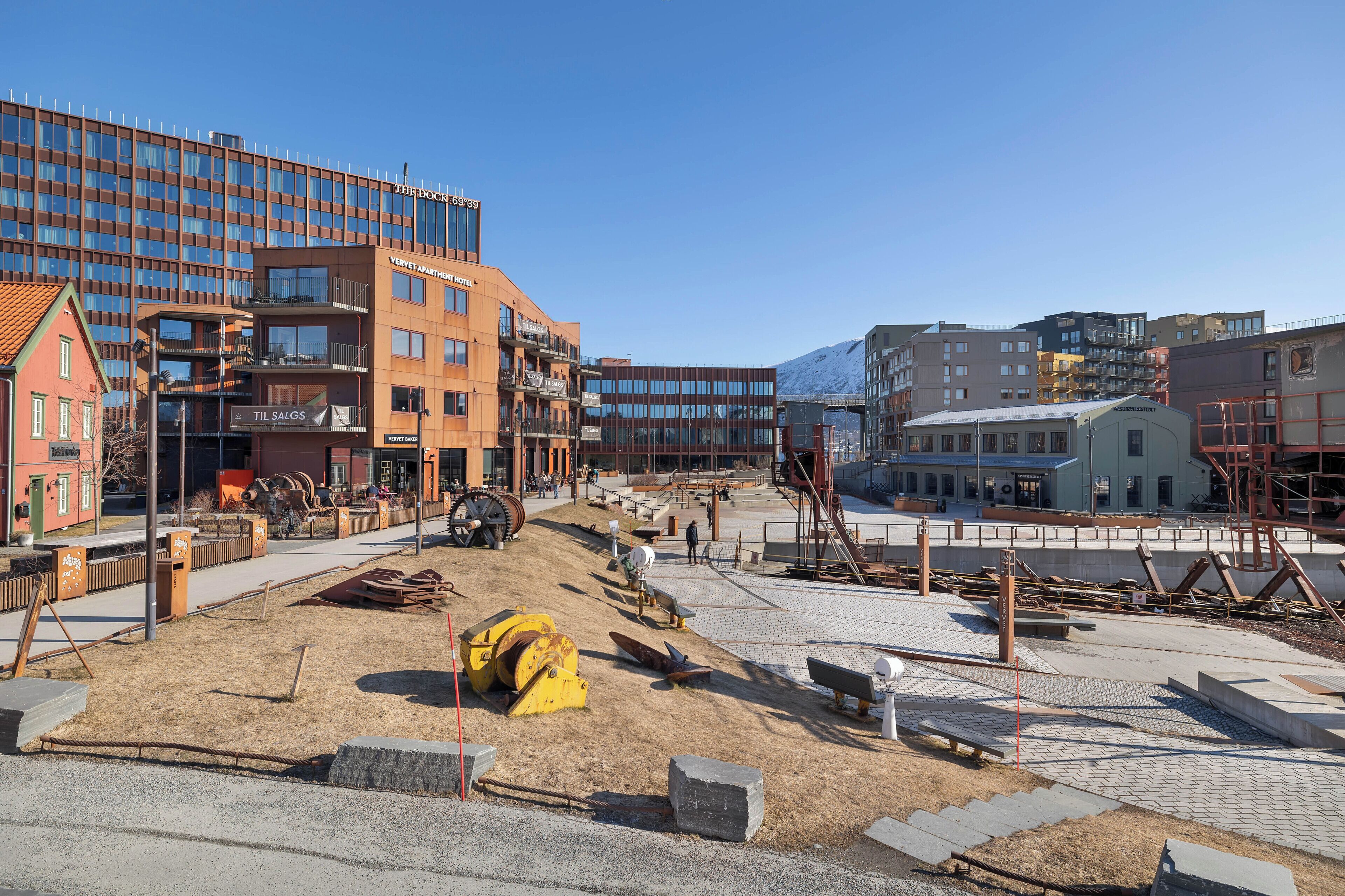 A construction site with a building under development, a parking area, and a view of surrounding buildings.