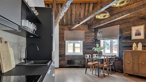 Et moderne køkken med træindretning, et spiseområde med bord og stole, samt et stort vindue.