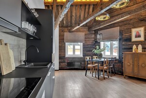 Una cocina moderna con detalles de madera, un comedor con mesa y sillas, y un ventanal grande.