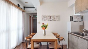 A modern kitchen with a dining area, wooden chairs, a white table, and a vase of flowers. - Ikebukuro 11-min walk | Private 6BR home | 77㎡, 2 baths | Ideal Tokyo base (Toshima-ku)