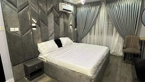 Un dormitorio moderno con una cama grande, una mesita de noche, una silla y un escritorio.