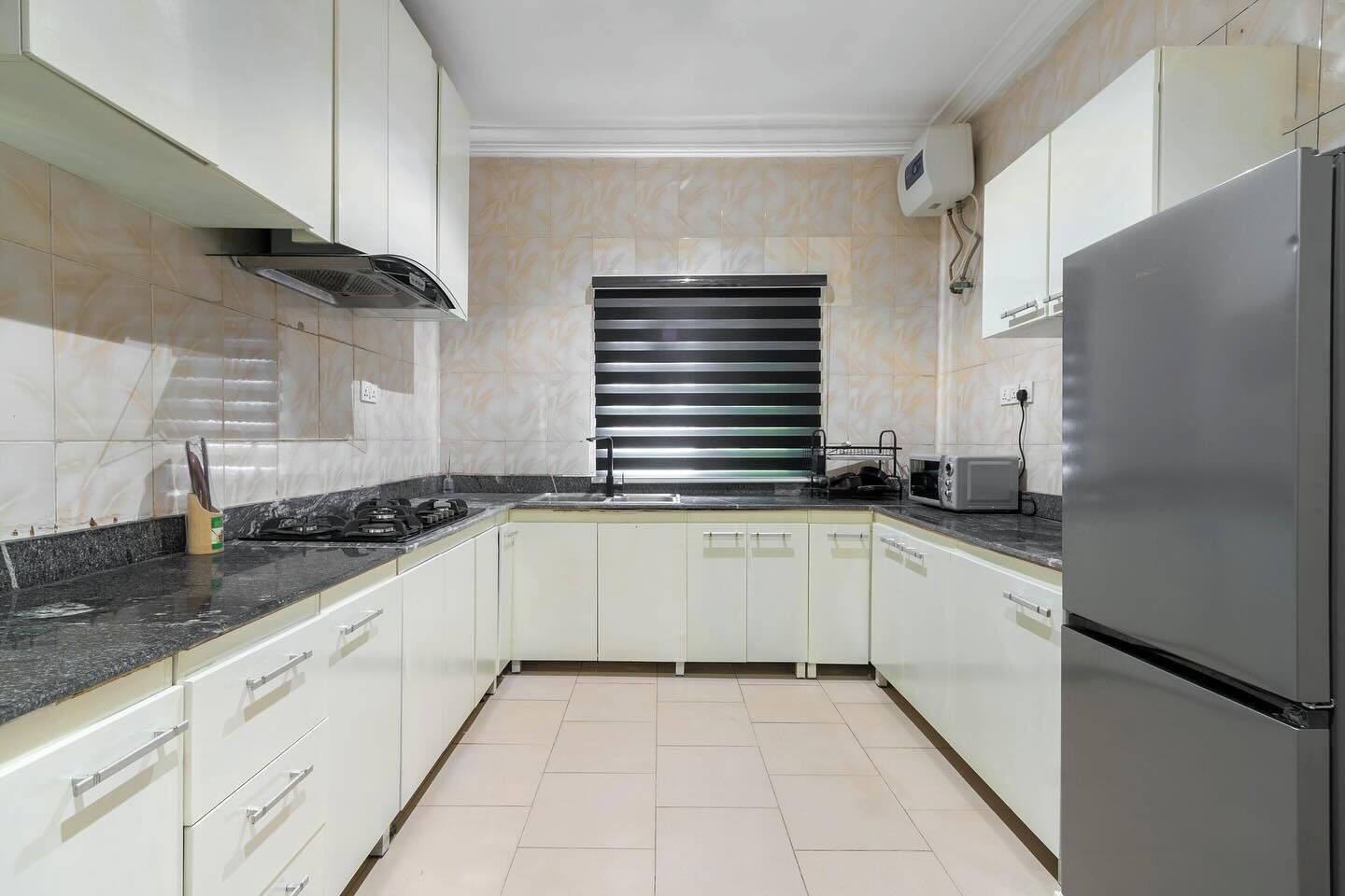 A kitchen with white cabinets, a stainless steel refrigerator, a gas stove, and a microwave.