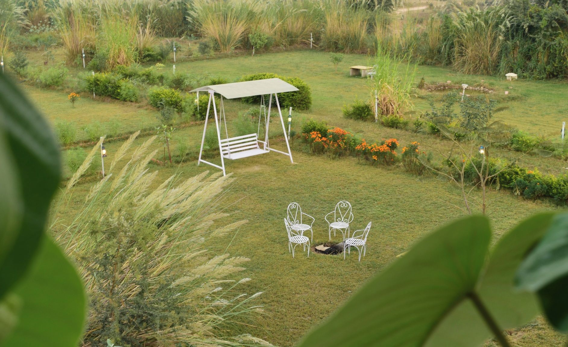 Un jardín con un columpio, dos sillas y un banco.