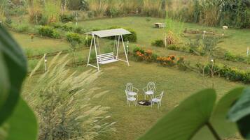 Un jardín con un columpio, dos sillas y un banco.