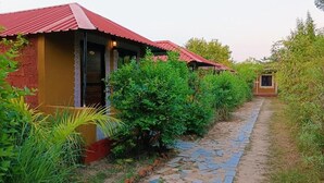 Une rangée de bâtiments de style rustique, avec des toits rouges et un sentier de pierre qui traverse un jardin luxuriant.