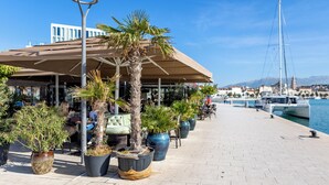 Een restaurant aan het water met terras, potplanten en uitzicht op de jachthaven.