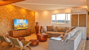 A modern living room with a large flat-screen TV, a sofa, a coffee table, and a patterned wall. - Stylish Desert Retreat - Hot Tub, Game Room, Fire Pit, Minutes to JTNP (Twentynine Palms)