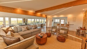 A spacious living area with a large sofa, a round coffee table, and a dining area with wooden chairs and a table. - Stylish Desert Retreat - Hot Tub, Game Room, Fire Pit, Minutes to JTNP (Twentynine Palms)